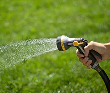 Hände Rasen bewässern Gartenschlauch Rasenpflege